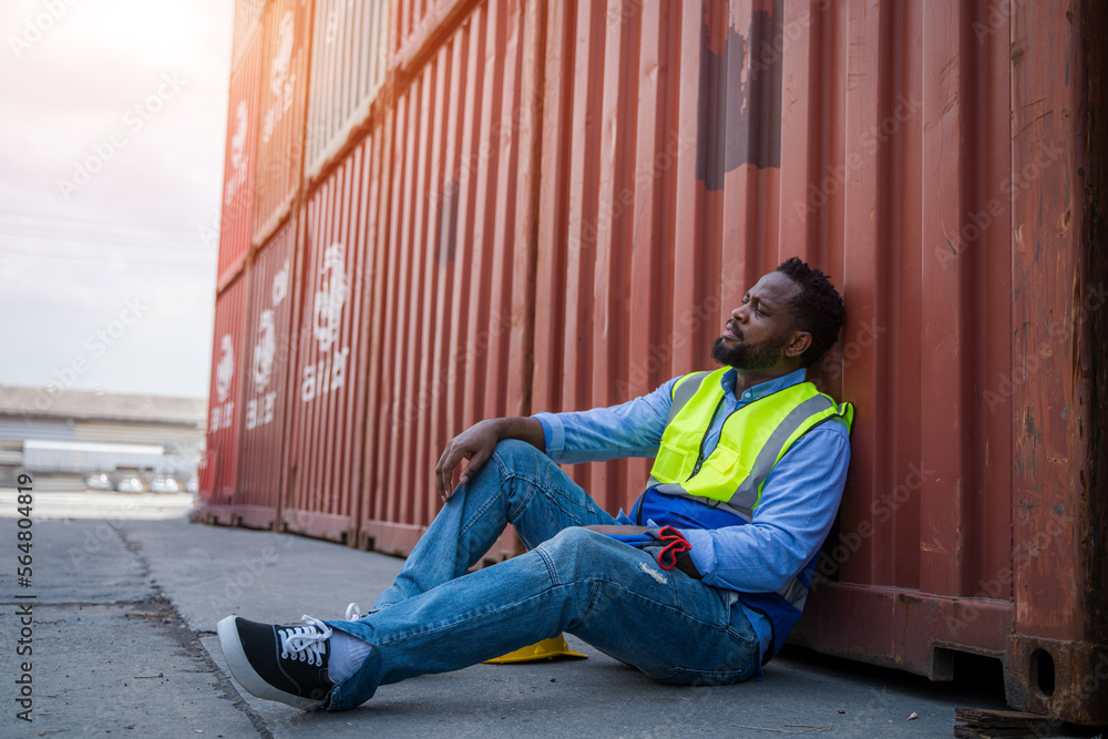 Poster Worker sitting and thinking of something while taking a break after working at container yards.