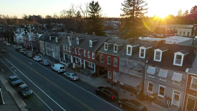 Slow aerial pass by row houses in American city. Beautiful sunset over winter scene.