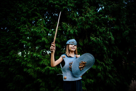 Low angle view of happy girl wearing armor costume while standing against trees at park