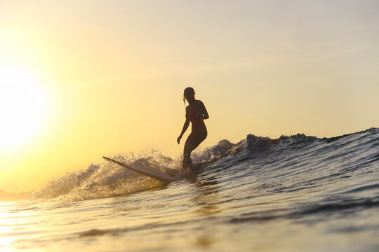 Young woman surfing at sunset