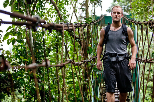 An adventure tourist crosses a suspension bridge en route to "The Pinnacle's", Mulu Natioanl Park, Sarawak Malaysia.