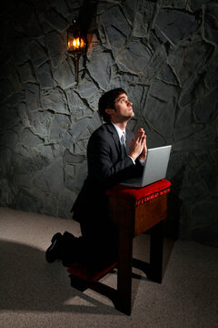 Businessman praying with laptop computer