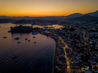 Sunset drone view of Bodrum castle and houses on the beach and boats in the sea