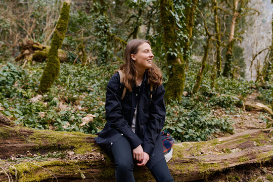 young woman travels through an old dead forest with a backpack