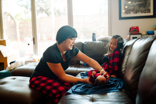 Mom at home with children dressing her baby in a pajama