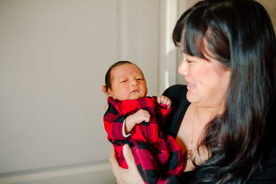 Happy Smiling Mother Holding Her Newborn Baby Boy Up In Her Arms