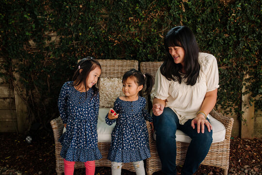 happy smiling mother with her toddler daughters in the backyard