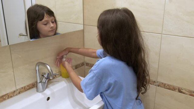 The kid washes his hands with soap. A little girl washes her hands under running water.