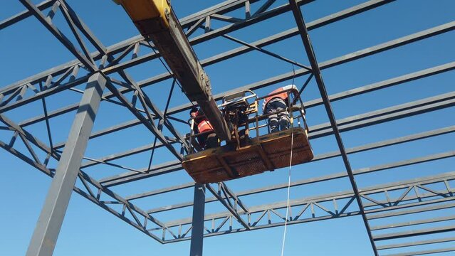 High elevated cherry picker with rigger on construction site.