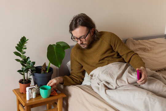 man takes a mug of tea lying in bed