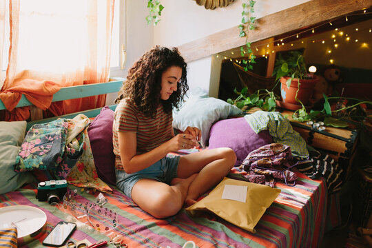 Brunette girl sitting on her bed and packaging a second hand product