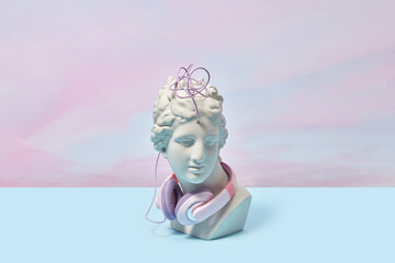 Greek bust entangled in wire of headphones.