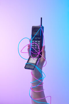 90s cell phone in woman's hand in neon wires.