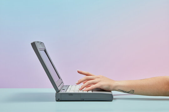 Retro 90s laptop with hands of working woman.