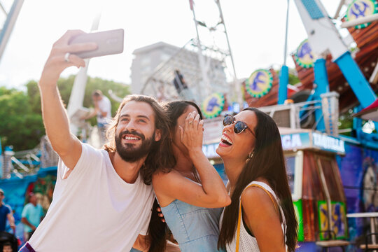Man taking selfie with women in amusement park