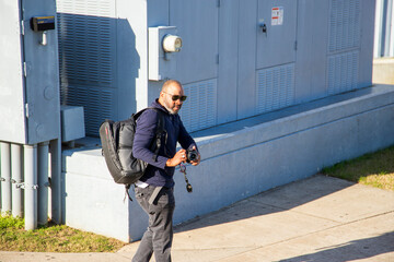 an African American walking along a footpath with a camera and a backpack at USS Alabama Battleship...