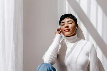 Smiling young lady enjoying music in TWS earphones