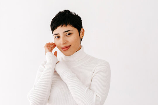 Hispanic female with pixie cut touching face
