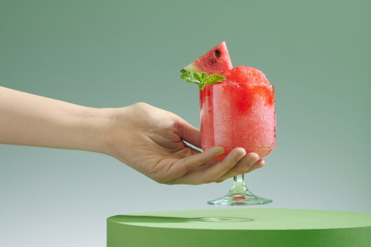 Holds glass of watermelon granita shaved ice dessert flavored.