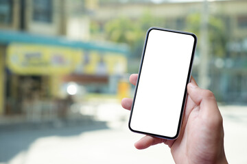 Close up view of man hand holding smartphones with blurred sunrise and building on background.