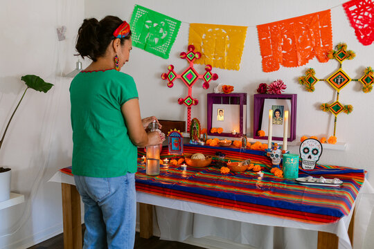 Mexican decorating her domestic altar with offerings