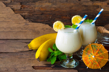 Banana fresh cocktail vanilla smoothies  fruit juice beverage healthy the taste yummy in glass drink episode good morning on wooden background from the top view.