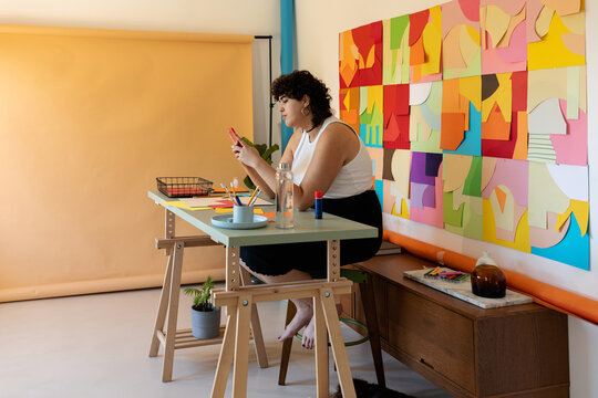 Woman checking phone in colorful studio