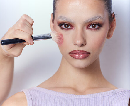 Androgynous woman With creative Make Up and a brush on her check