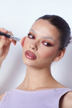 Androgynous woman With creative Make Up and a brush on her check