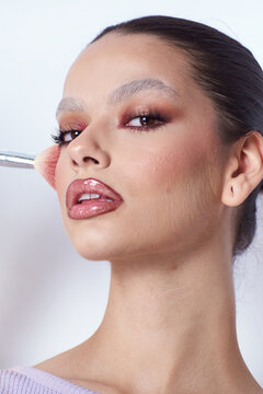 Androgynous woman With creative Make Up and a brush on her check