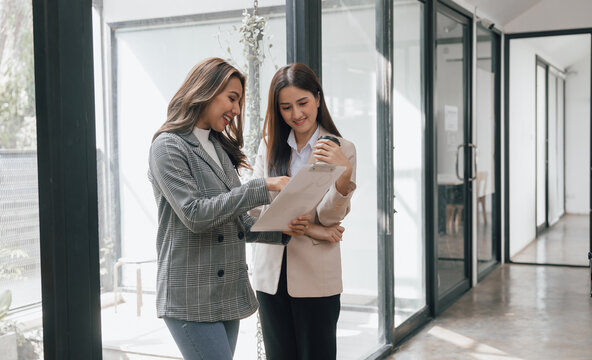 Two Young Pretty Asia Business Woman In Suit Talking Together In Modern Office Workplace, Thai Woman, Southeast Asian, Standing