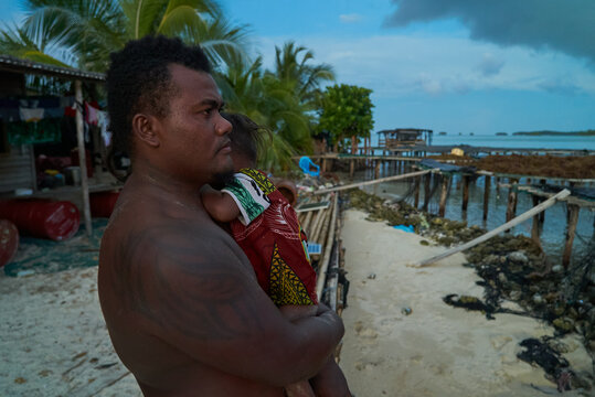 Solomon Islander man & baby faces intergenerational  sea level rise