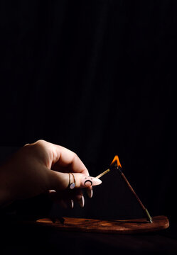 Woman's Hand Lights Incense with a Match