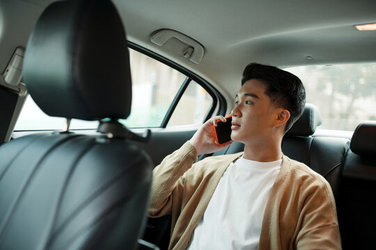 Casual man talking by smartphone in the car.