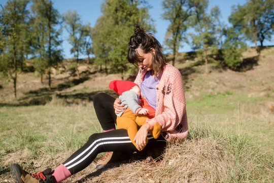 Breastfeeding a baby sitting on mountain field