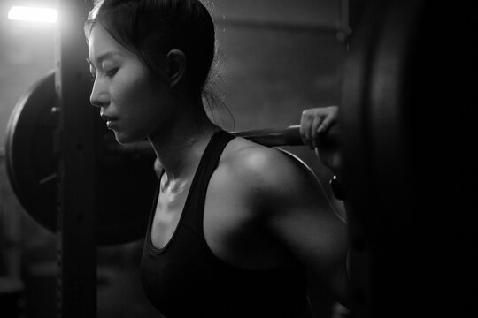 Young Asian female training in gym with weights at night