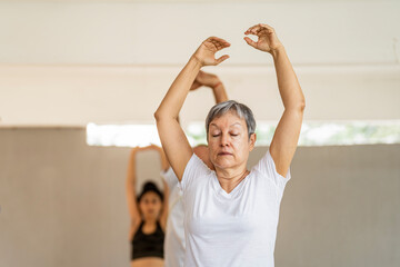 Older woman in yoga class with raised arms