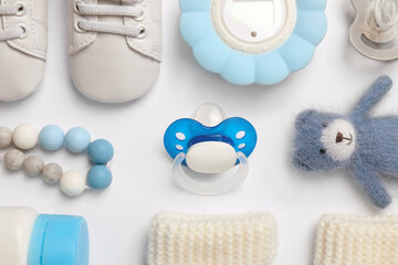 Flat lay composition with pacifiers and other baby stuff on white background