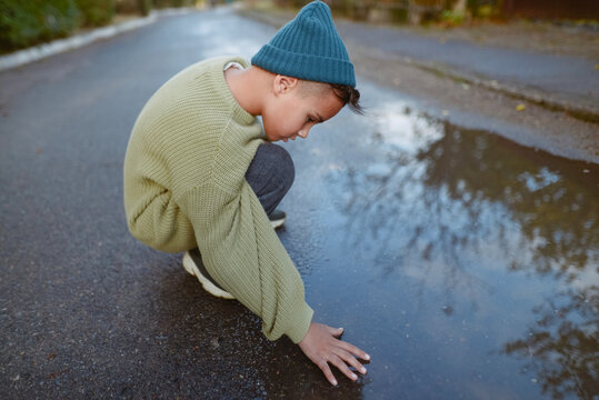 boy sitting near a puddle