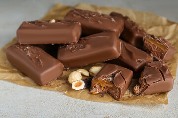 Delicious chocolate candy bars with nuts on light table, closeup