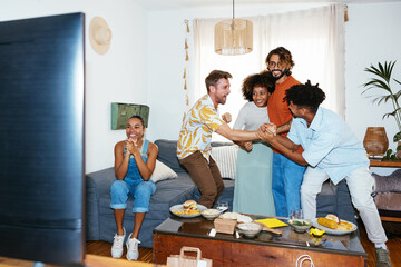 Group of diverse friends celebrating victory at home