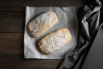 Raw dough for ciabatta and flour on wooden table, flat lay