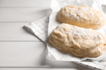 Raw dough and flour on white wooden table, space for text. Cooking ciabatta