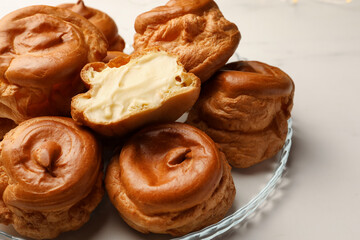 Delicious profiteroles with cream filling inside on white table
