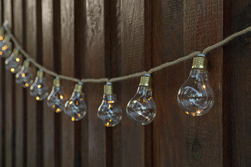 Garland of lamp bulbs hanging on wooden wall. String lights