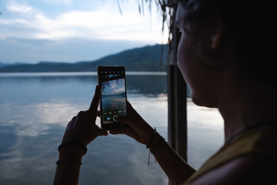 woman taking a photo at a lake