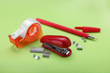 New bright stapler with stationery on green background