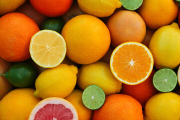 Many different whole and cut citrus fruits as background, top view