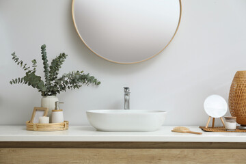 Stylish mirror, eucalyptus branches and vessel sink in modern bathroom. Interior design