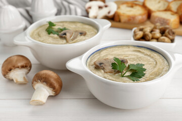 Delicious mushroom cream soup with parsley on white wooden table